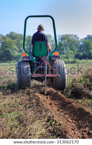 BLUEMONT, VA - AUGUST 29, 2015:  Unidentified farmer tilling potatoes in a field illustrating the work and lifestyle of the agricultural industry of farming in Northern Virginia.