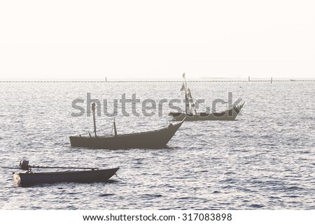 Silhouette fishing boats float slowly on the sea against clear sky.Used color tool for soft tone and vintage tone.