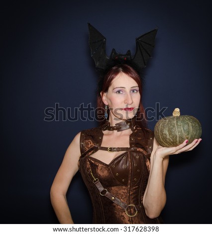 Funny portrait of girl with pumpkin and bat wings on the hair
