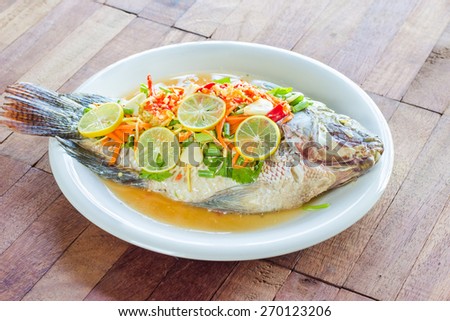 steamed Nilotica fish,thai style steamed fish in spicy sauce,wood background