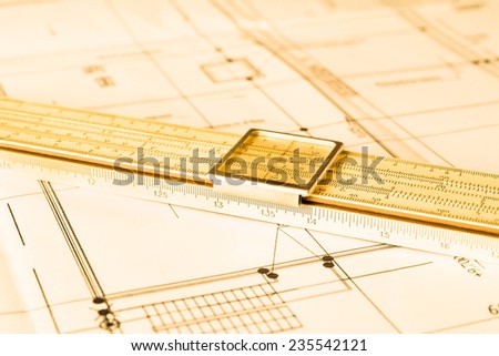 Schemes and slide rule on the table. Angle view, in yellow tone