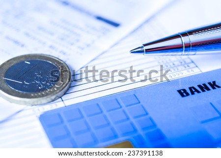 Pay the bills, bank card and pen with check on the table. In blue tone