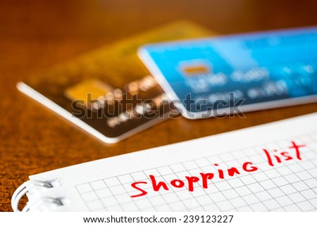 Shopping list, a notebook with shopping list and a credit cards on the table
