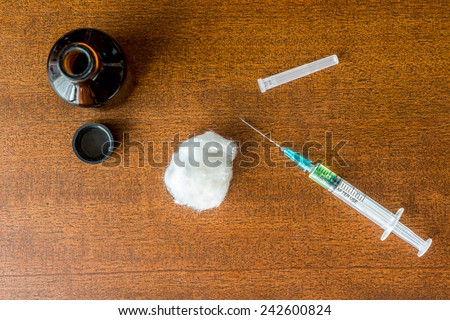 Cure the disease, a solution, and a syringe for injection with wadding on the table. Top view