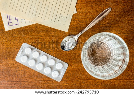 Cure the disease, tablets in the spoon with a glass of water and prescriptions from the doctor on the table