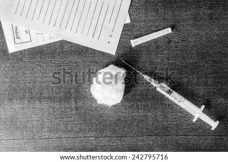 Cure the disease, syringe injection and prescriptions from the doctor on the table. Top view, in the black and white colors