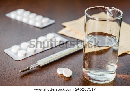 Cure the disease, a tablets  with a glass of water and prescriptions from the doctor on the table. Angle view, focus on the tablets