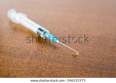 Medicine flows from the syringe and spread out on the table. Angle view