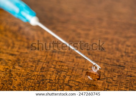 Medicine flows from the syringe and spread out on the table. Angle close up view