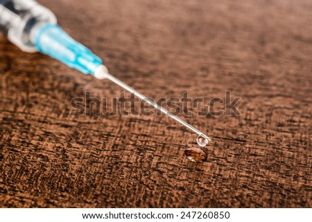 Medicine flows from the syringe and spread out on the table. Angle close up view, in old tones