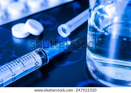 X-ray examination, syringe for injection and glass of the water with a two pills for treatment of disease. In blue tones