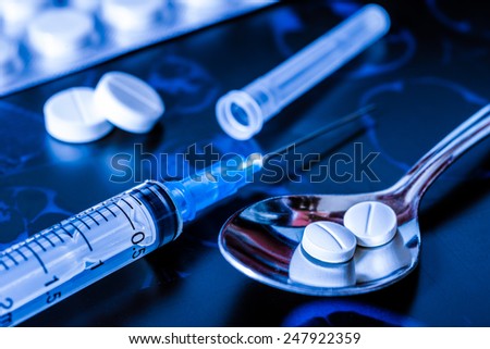 X-ray examination, syringe for injection, a pills in the spoon for treatment of disease. In blue tones