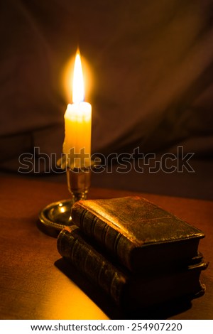 Bible and old books and candle on a wooden table. Focus on the old books