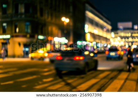 Night city, cars at night with pedestrian on the avenue. Image in yellow-blue toning