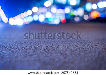 Nights lights of the big city, close up view on the road from asphalt level. In blue tones