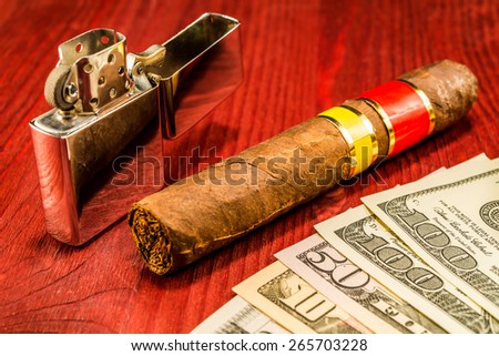 Cuban cigar and a several dollar bills with lighter on the table. Focus on the bills