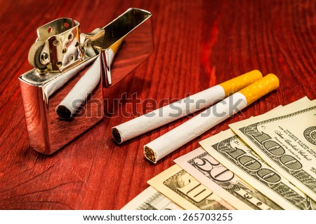 Couple of cigarettes and a several dollar bills with lighter on the table. Focus on the cigarettes