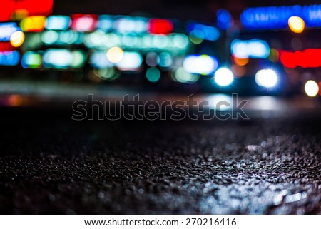 Nights lights of the big city, glowing shop windows and cars on the avenue. In blue tones