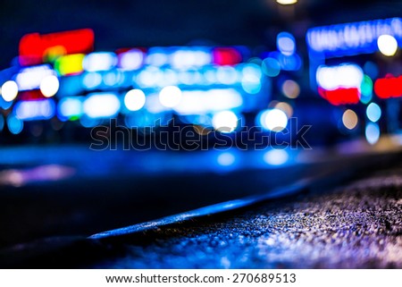 Nights lights of the big city, glowing shop windows and cars on the avenue, in blue tones