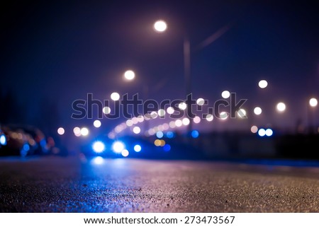 City night lights, road bridge with the lights and moving car in the fog after rain. View from the level of asphalt, in blue tones