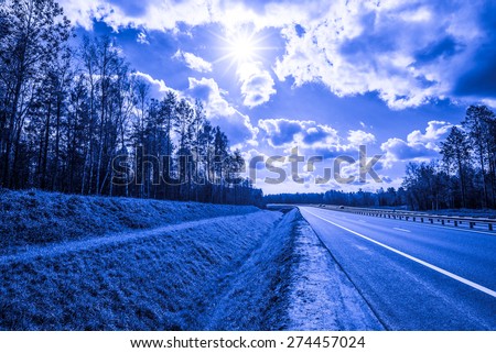 Midday sun on country roads in the forest. Image in the blue toning