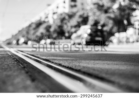 Sunny day in a city, view of the flow of cars approaching from the level of the tram rails. Image in the black and white tones