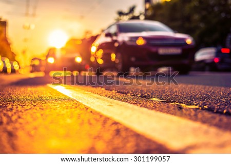 Sunny day in a city, view of the approaching cars to the road level. Image in the orange-purple toning