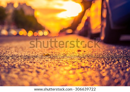 Sun after the rain in the city, view of the headlights of the approaching cars with the road level. Image in the yellow-purple toning