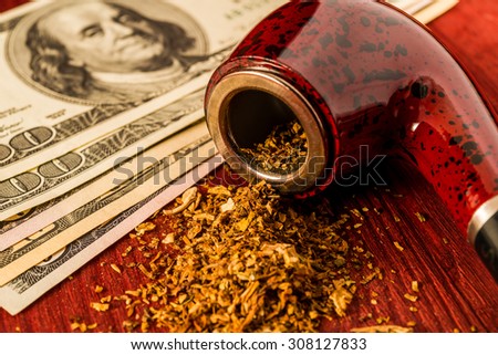 Tube for smoking tobacco and money on a wooden table. Close up view, focus on the tube