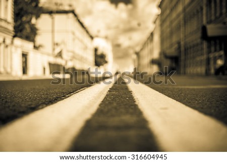 Clear day in the big city, empty city street. View of the road at the level of the dividing line, image in the yellow toning