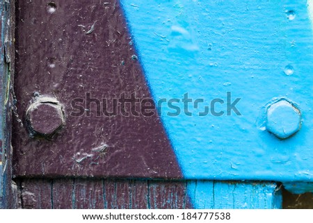 Wooden surface painted in beautiful colors and shapes with partly peeled paint and screws