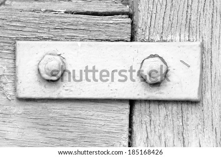 Black and white photography of wooden surface painted in beautiful colors and shapes with partly peeled paint and screws