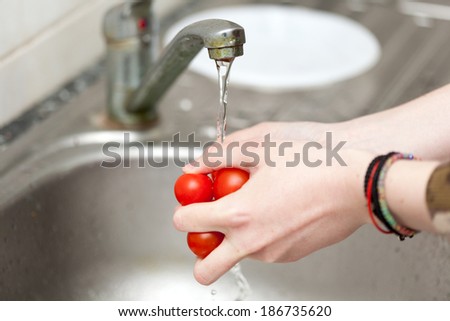 Woman hands washing cherry tomatoes - food texture and colors