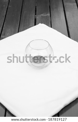 Black and white, moody ornamental arrangement with  candle  on a white table cloth on a wooden table