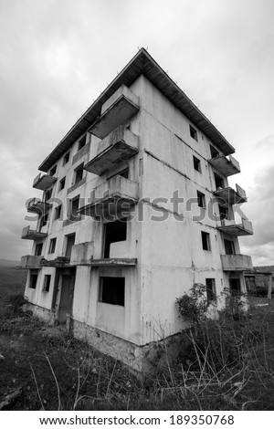 Black and white abandoned block of flats under construction. Brick and cement textures with grass around it. Fish eye lens effect