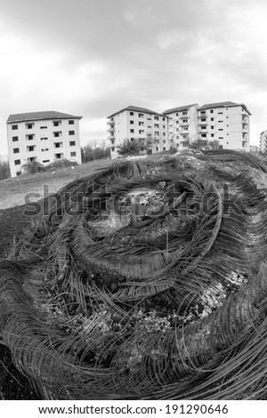 Black and white abandoned block of flats under construction with burnt metallic wires