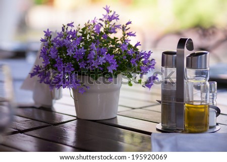 Moody ornamental arrangement with plant with blue flowers on a wooden table and green texture in the background