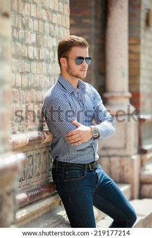 Handsome young man wearing a blue shirt and jeans. Street shooting in Timisoara, Romania