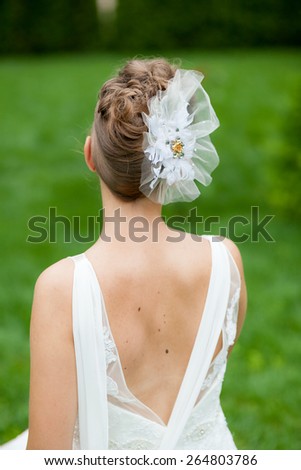 Beautiful, caucasian, brown haired woman wearing a wedding dress with natural, green background