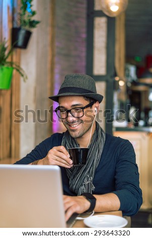 Fashionable and stylish young man relaxing with coffee, music and internet browsing at the cafe bar. Selective focus. Toned image