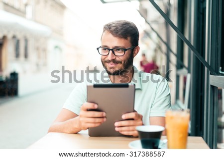 A young man working on a digital tablet in a restaurant. Natural light, Selective focus.