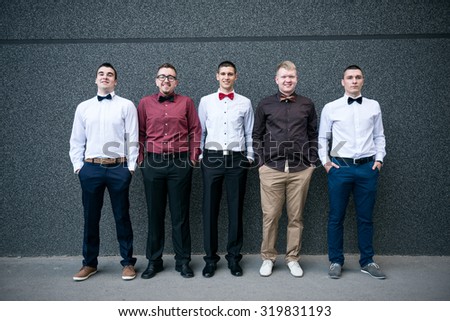 Young successful self confident businessmen standing in front of the wall with a crossed arms.