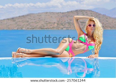 Beautiful woman lying by the pool in a sexy swimsuit in Santorini