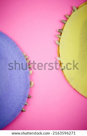 Purple and yellow typical Mexican wafers with  pumpkin seeds or pips and honey over a pink background. Imagine de stoc © 