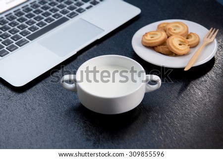Table at the cafe with a cup of coffee, cookies and a laptop, Laptop computer, notebook and cup of milk chocolates on wooden background ( Space and composition for text )