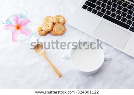 Table at the cafe with a cup of coffee, cookies and a laptop next to a window
