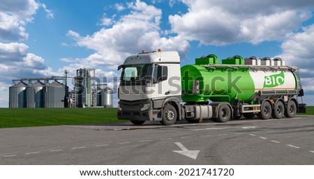 Truck with a tank with the inscription BIO on the background of silos. Biofuel concept.