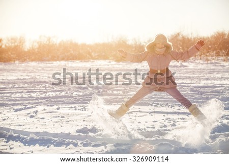 Girl jumping in the snow-covered park. Photographed in backlit. Snow fly away. Silhouette.