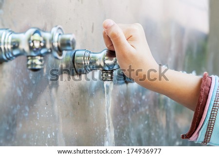 Child\'s hand with drinking water running from tap water