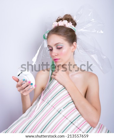 Girl-marshmallow with a pillow and alarm clock in her hands. Girl with makeup in the style of marshmallow, beauty fantasy. Young woman with a gentle make-up and hairstyle, decorated with candy.